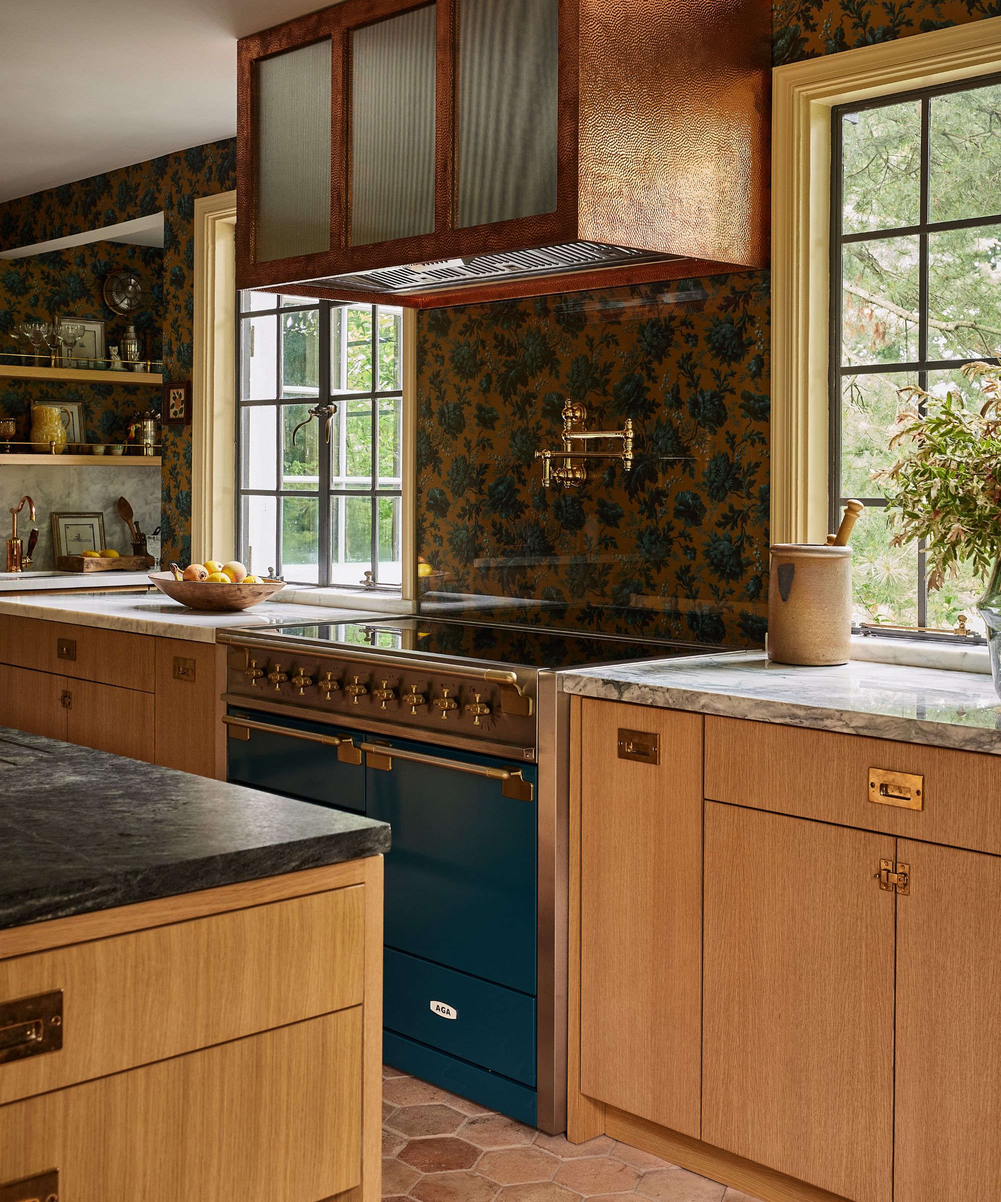 a cozy warm mustard and wood kitchen with wallpapered walls, a large kitchen island with a farmhouse wooden table