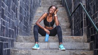 Woman sits on steps looking happy after completing a run