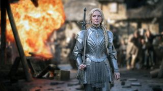 Morfydd Clark (Galadriel) is clad in armor and walks with a fire raging behind her in Lord of the Rings: The Rings of Power