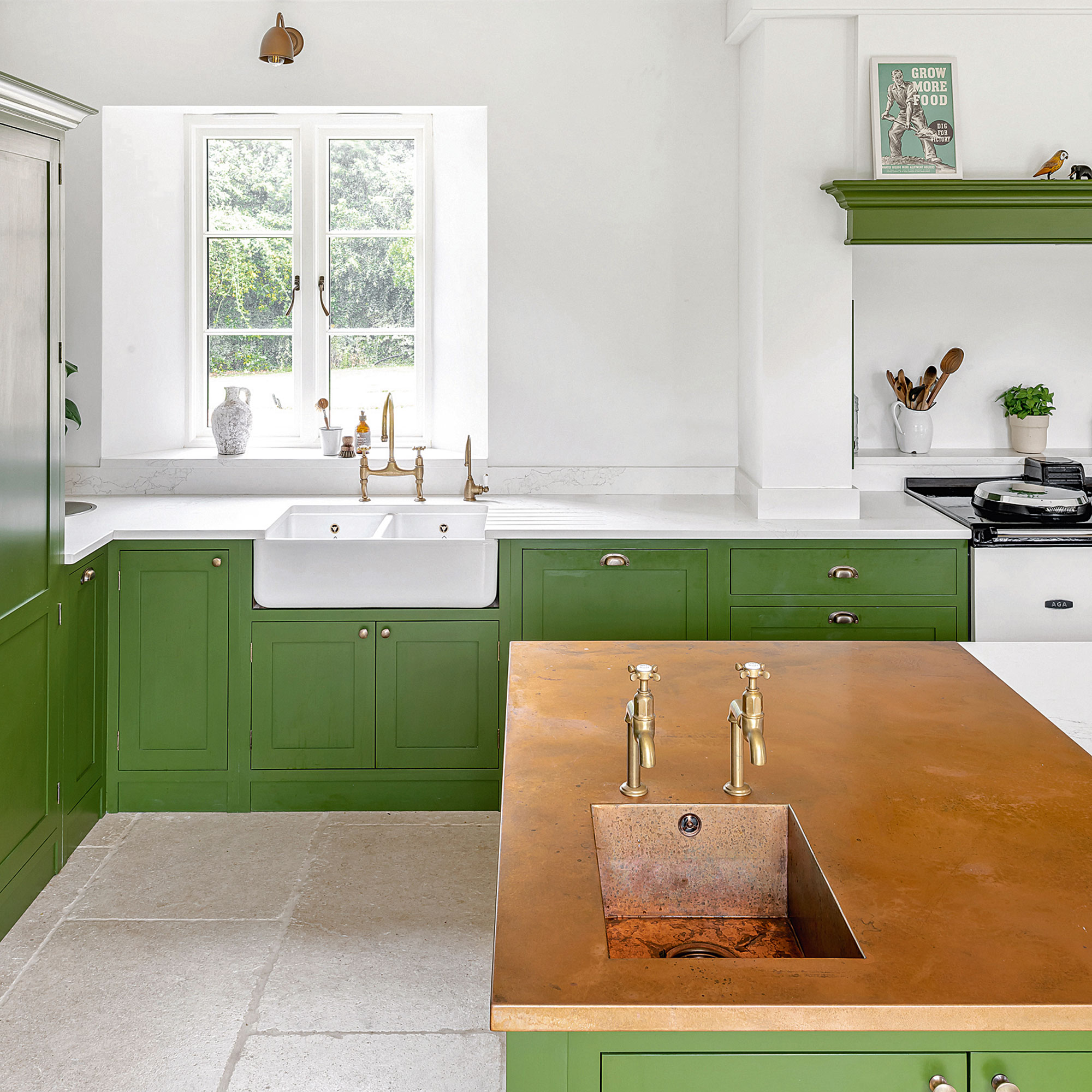 Green kitchen with white work tops and wall, with a large kitchen island and copper sink