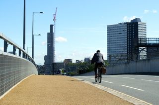 Image shows a rider cycle commuting to work by bike to reap the benefits.