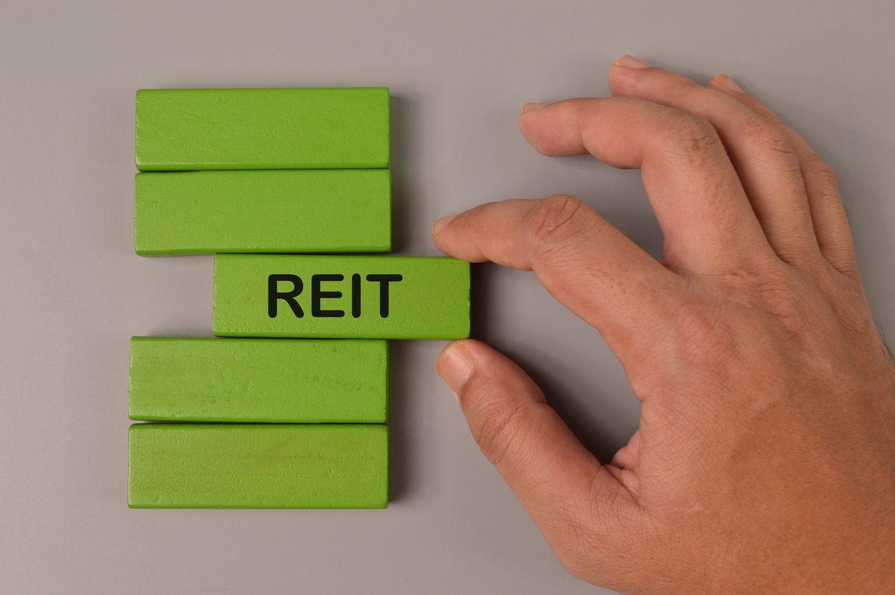 Hand picked wooden block written with Reit, which stands for Real Estate Investment Trust 