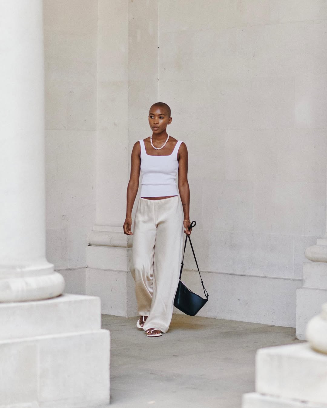 Marisa wearing silk trousers and white vest