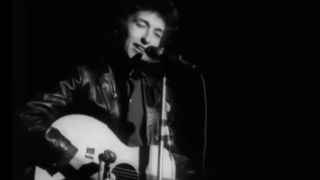 Bob Dylan in black and white, playing guitar and singing in Don't Look Back