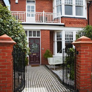 Front of brick house with black and white tiled path