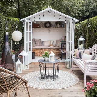 white garden shed white bench with cushions wooden flooring and trees