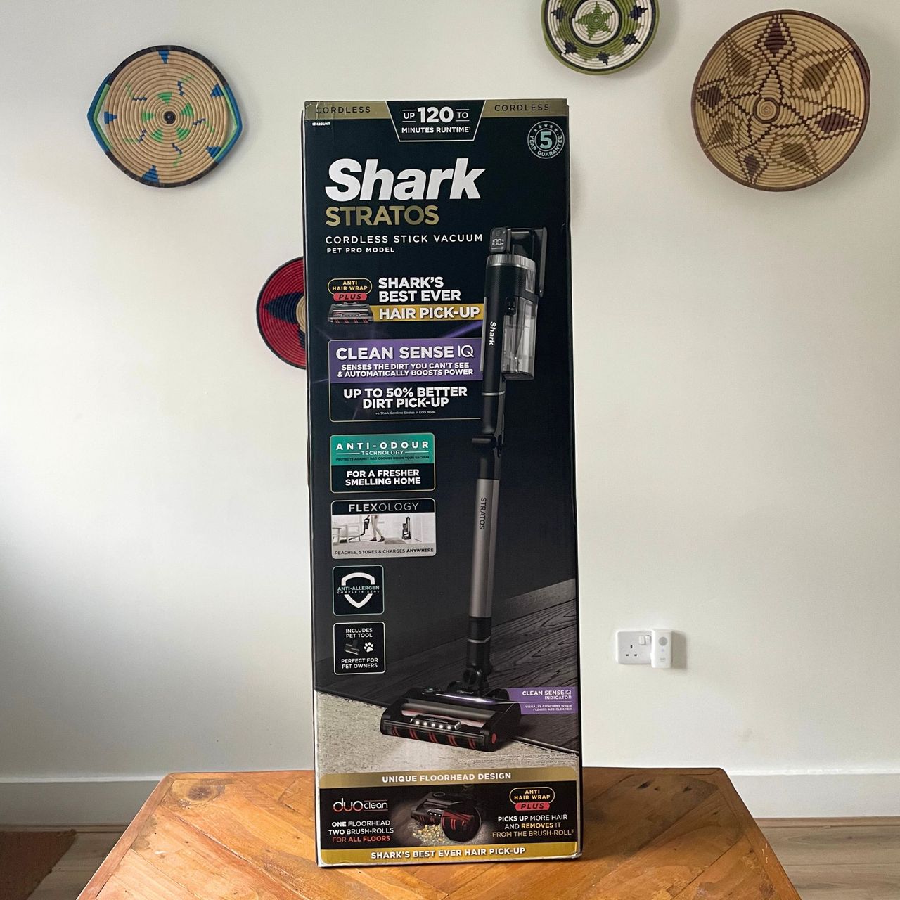 Shark Stratos Cordless Vacuum box sitting on a wooden table in front of a white wall