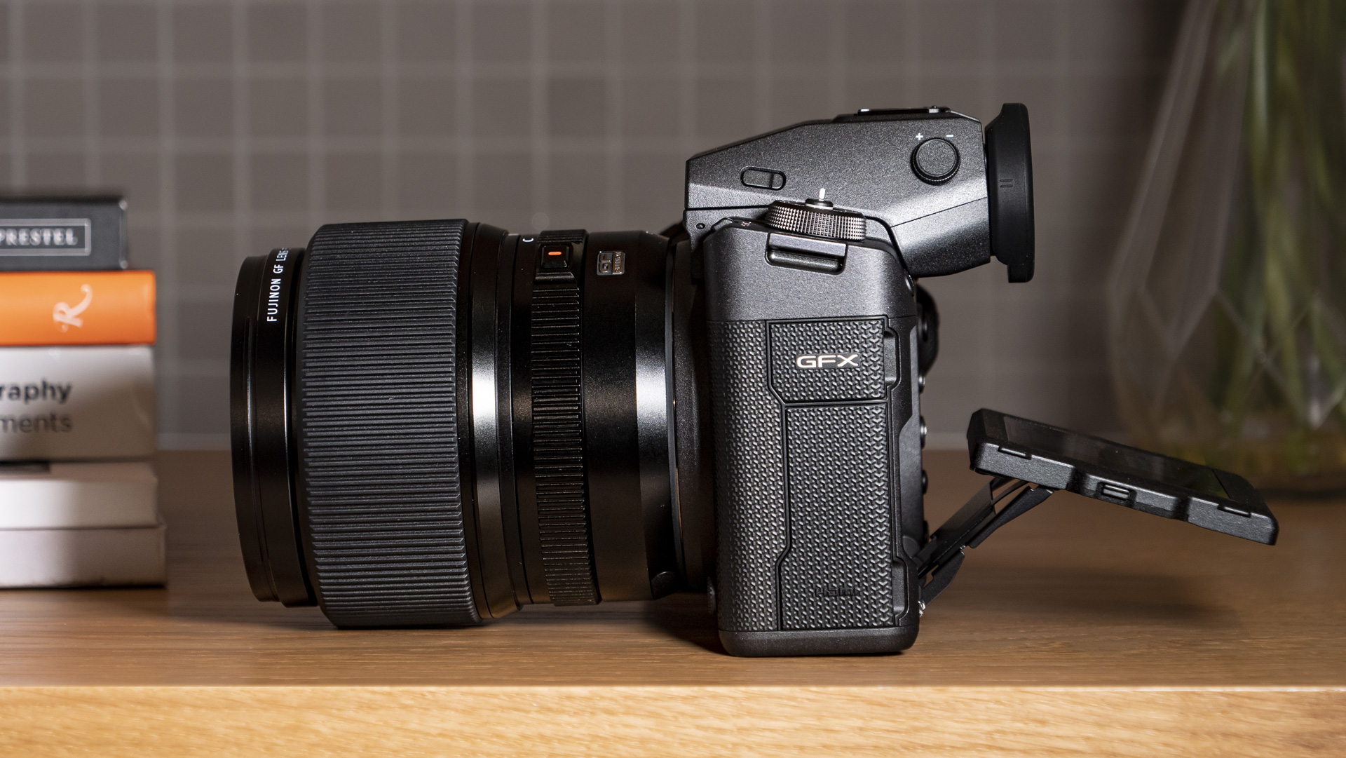 Fujifilm GFX100 II on a wooden table, side profile with LCD screen tilted