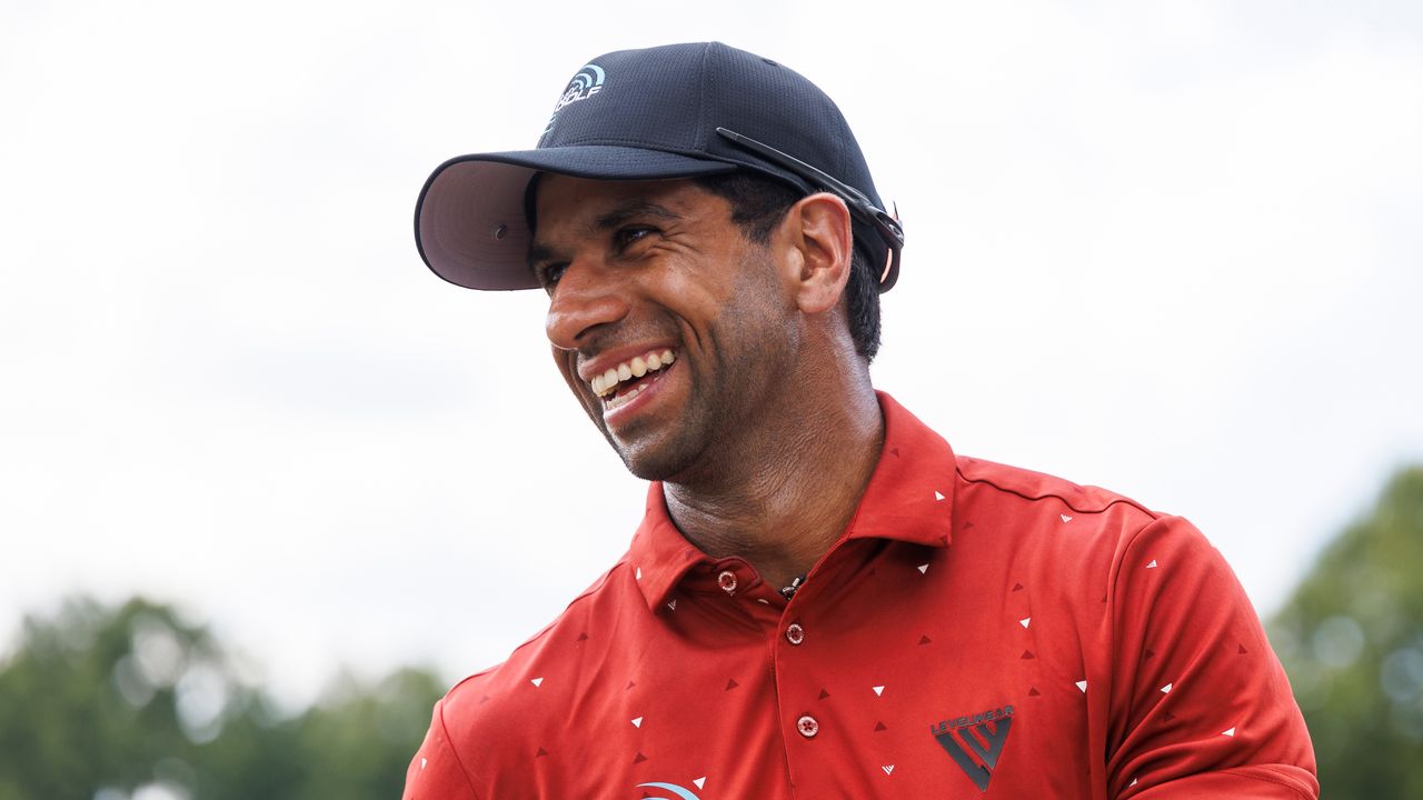 Aaron Rai laughs in a red polo and black cap at the 2024 FedEx St Jude Championship