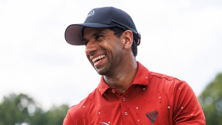 Aaron Rai laughs in a red polo and black cap at the 2024 FedEx St Jude Championship