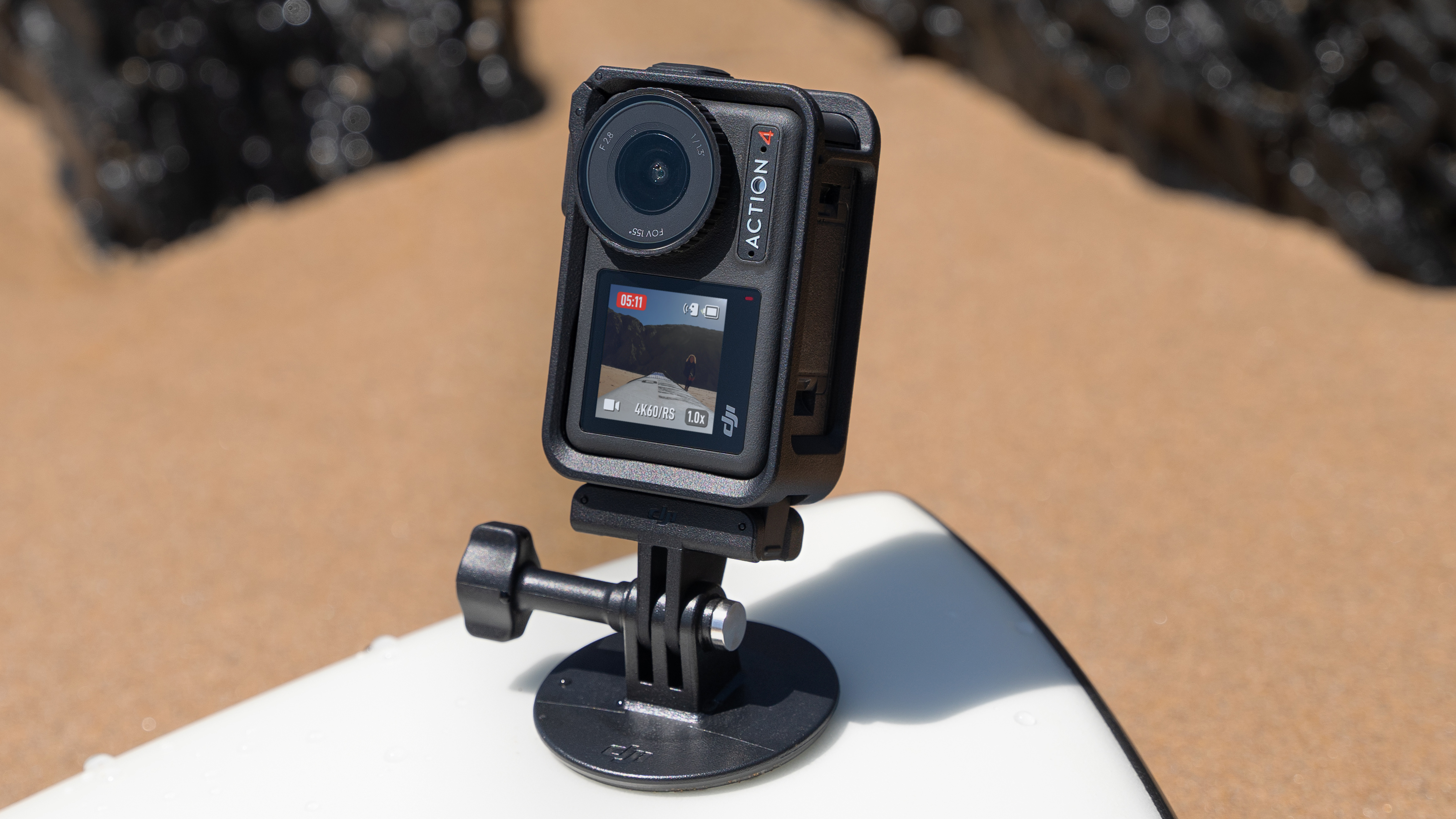 DJI Osmo Action 4 camera mounted to a surfboard on a sandy beach