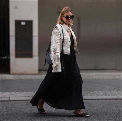 Aline Kaplan is seen wearing Polene Paris black round leather bag, Veronica Beard beige jeans jacket, Carolina Lemke black shades, Gestuz black maxi dress and Vagabond black sandals on May 25, 2022 in Berlin, Germany. 