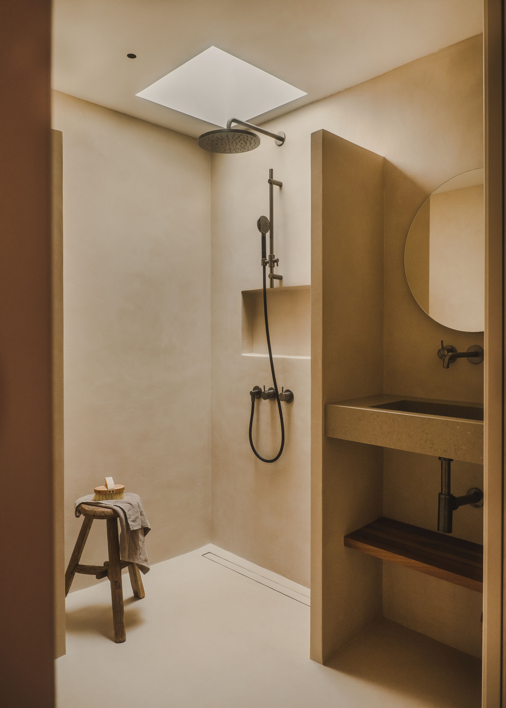 A walk-in shower with pale pink walls, a shower niche, and a small skylight