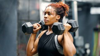 A woman performing a step to dumbbell press