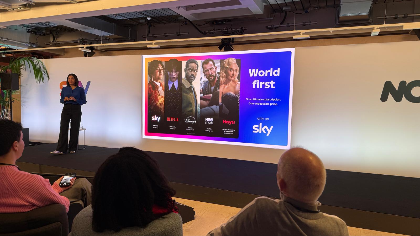 An image take at a press event, with a presenter on screen and a slide showing the new Sky Ultimate package