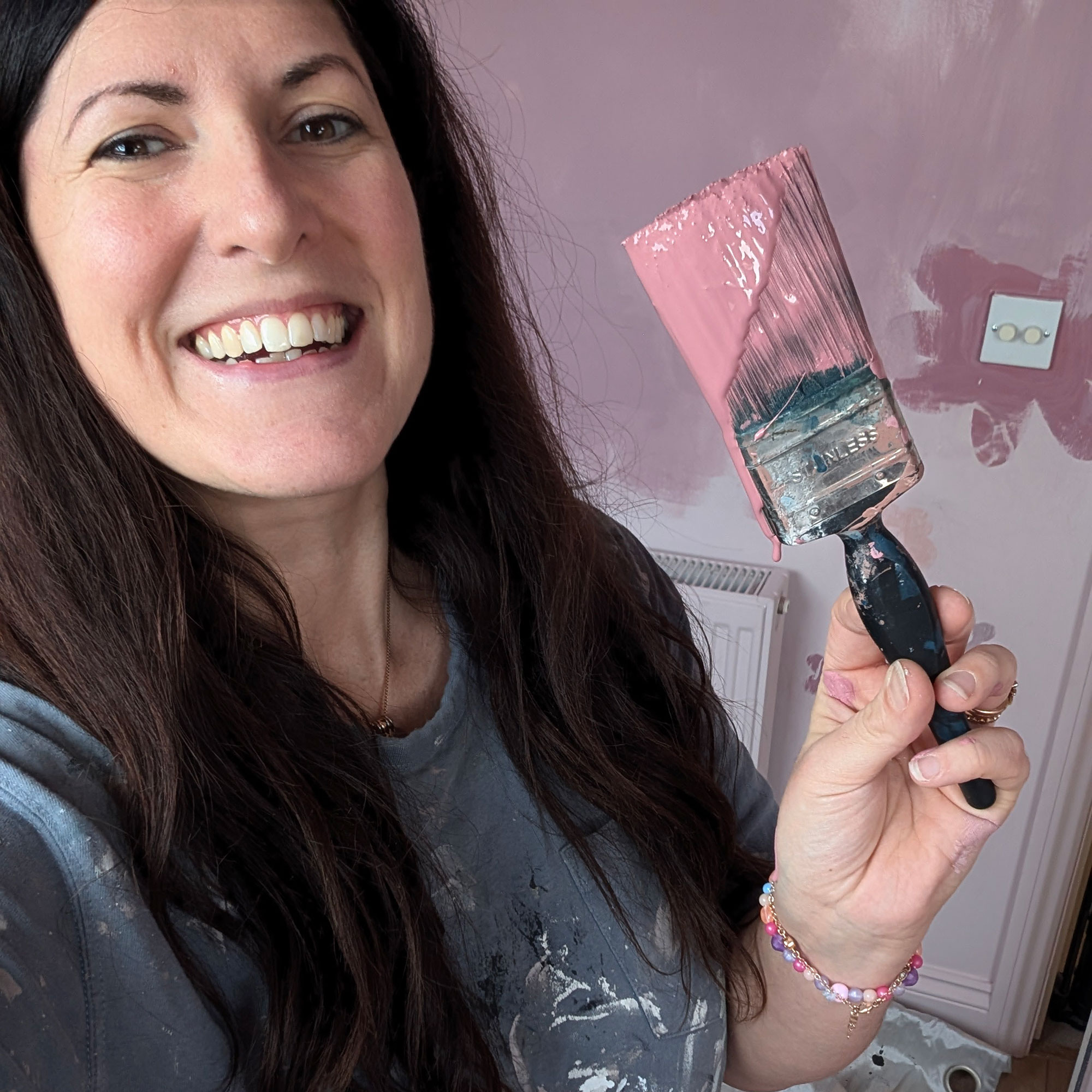 Woman holding paint brush covered in pink paint