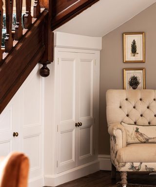 built-in storage under stairs with pheasant design armchair