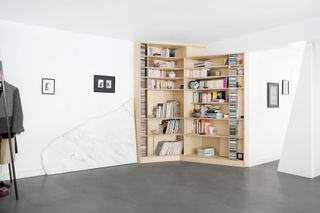 Custom-designed library by Sophie Dries in a room with white walls and framed pictures on the wall