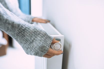Person setting thermostat on a radiator