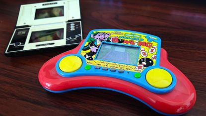 Sesame Street Number Bowling LCD game next to Nintendo Game and Watch Pinball on woodgrain desk.