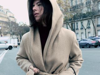 A model wearing an elegant hooded coat from Zara.