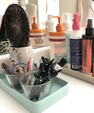 Jade colored tray on bathroom shelf with containers with hair accessories