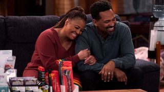 Kim Fields as Regina and Mike Epps as Bennie smiling on the couch in The Upshaws season 3