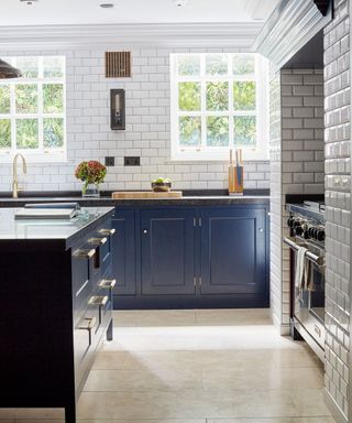 Kitchen wall lighting ideas with box light fixture in a white metro tiled kitchen with dark blue cabinetry.