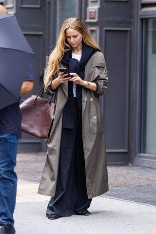 Jennifer Lawrences stands in New York City wearing a trench coat and the row's margaux bag