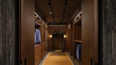 walk-in wardrobe with timber panelling, mustard yellow carpet, track lighting, mirror at the end of the closet