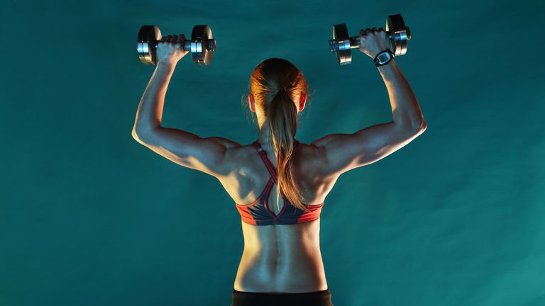 Woman works out her shoulders with set of adjustable dumbbells