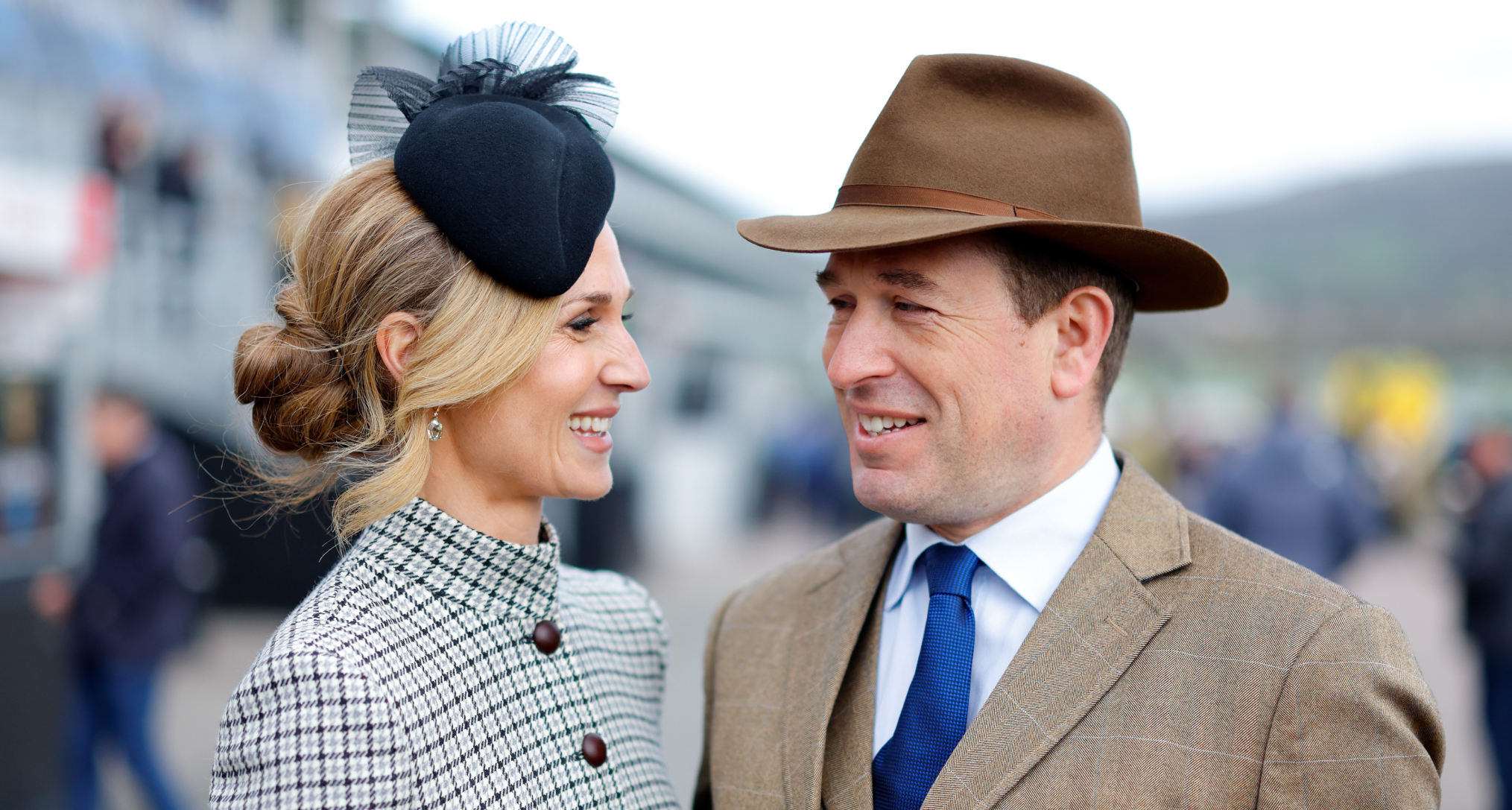 Harriet Sperling and Peter Phillips smiling at each other at Cheltenham races wearing hats