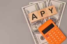 Money banknotes, calculator and wooden blocks written with APY.