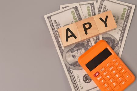 Money banknotes, calculator and wooden blocks written with APY.