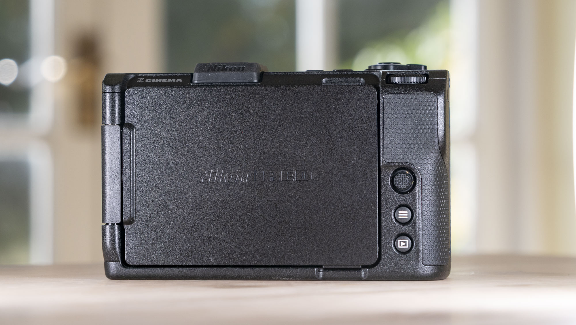 Nikon ZR product photos – camera on a wooden table, rear with screen folded away