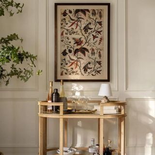 A bar cart with a large framed painting hanging above