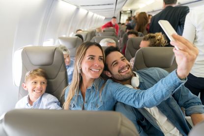 A happy family takes a selfie on an airplane.