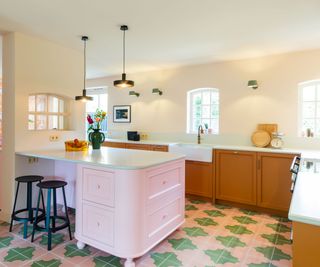 A pink, green and yellow kitchen with patterned floor tiles