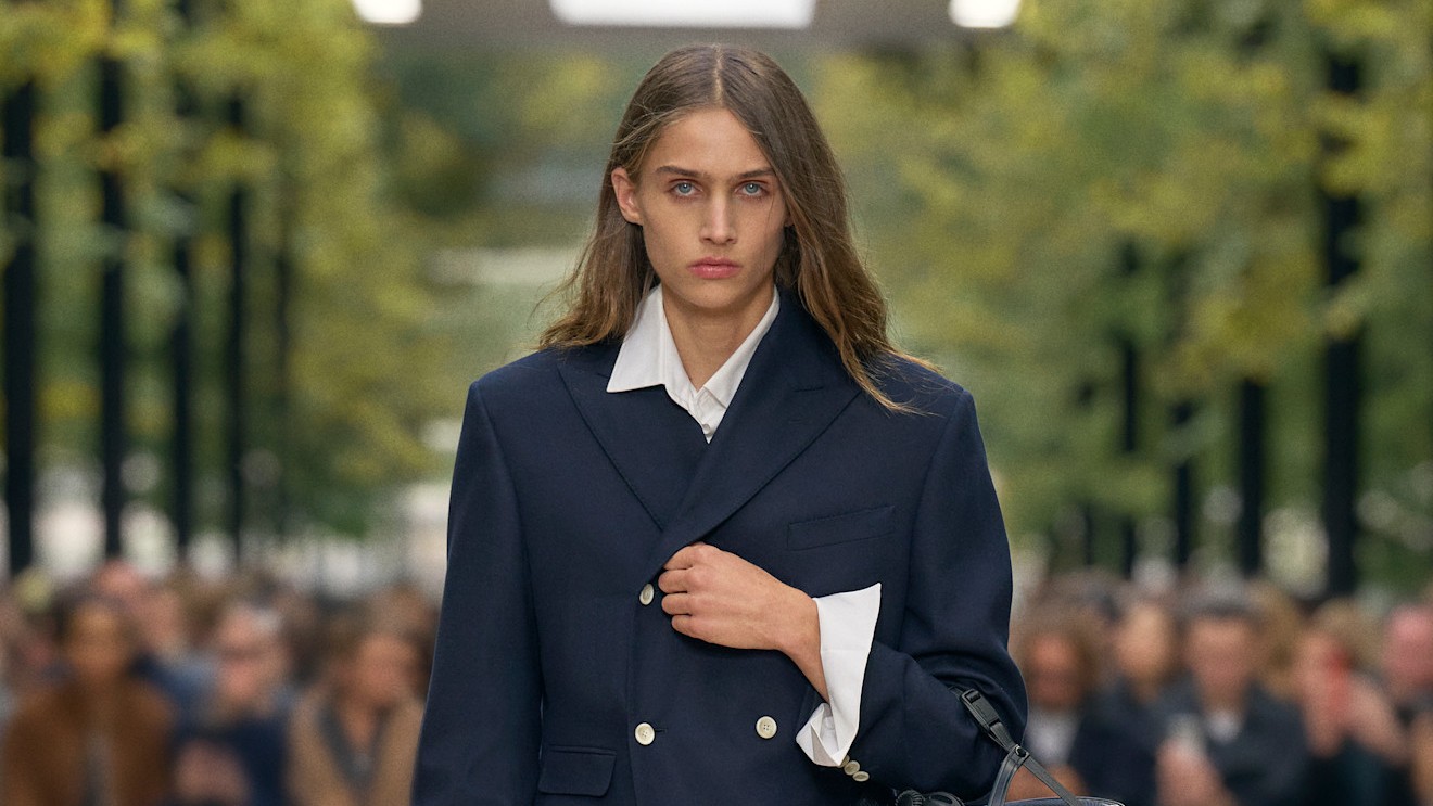 Model on the Celine S/S 26 runway wears structured double breasted jacket, wide leg white pants and Celine ballet lace up shoes.