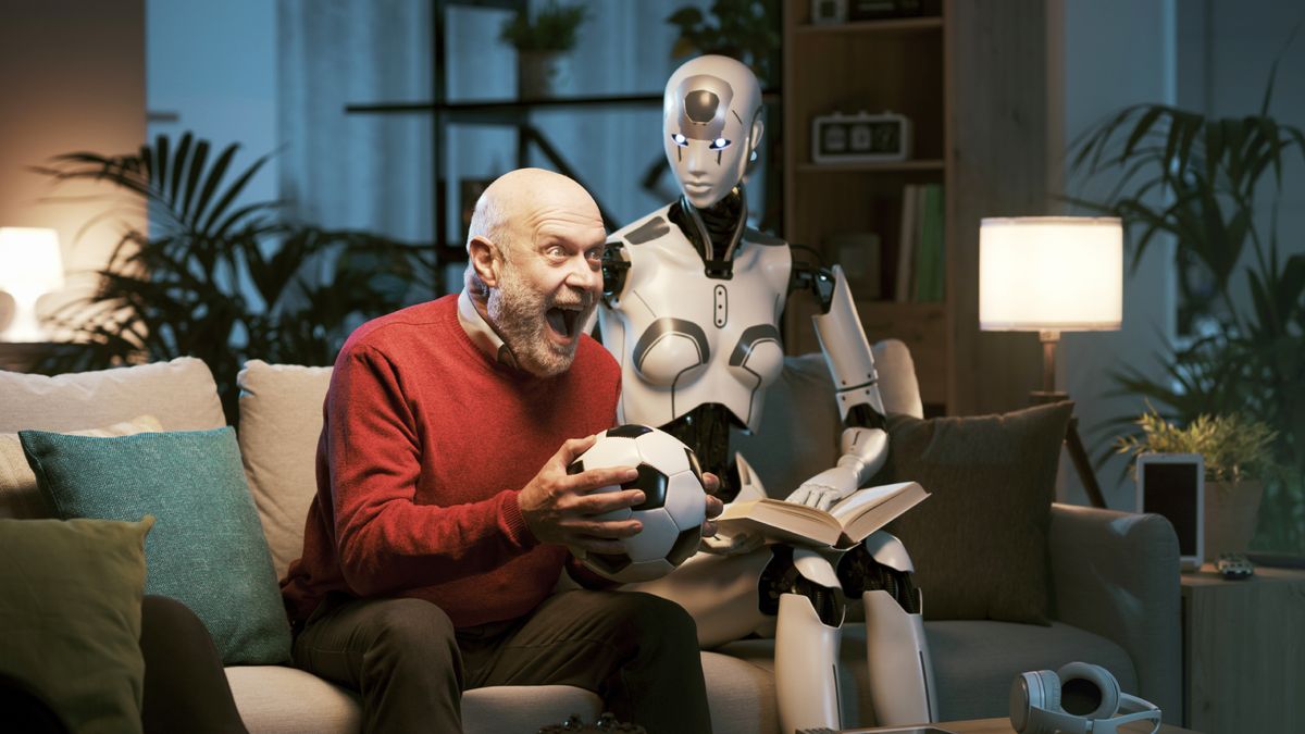 Man and humanoid robot spending time together at home, they have different hobbies and interests: the man is watching football on TV and the robot is reading a book