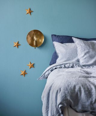 A bedroom wall lighting idea by Pooky with blue wall decor and Moon wall light in antique brass