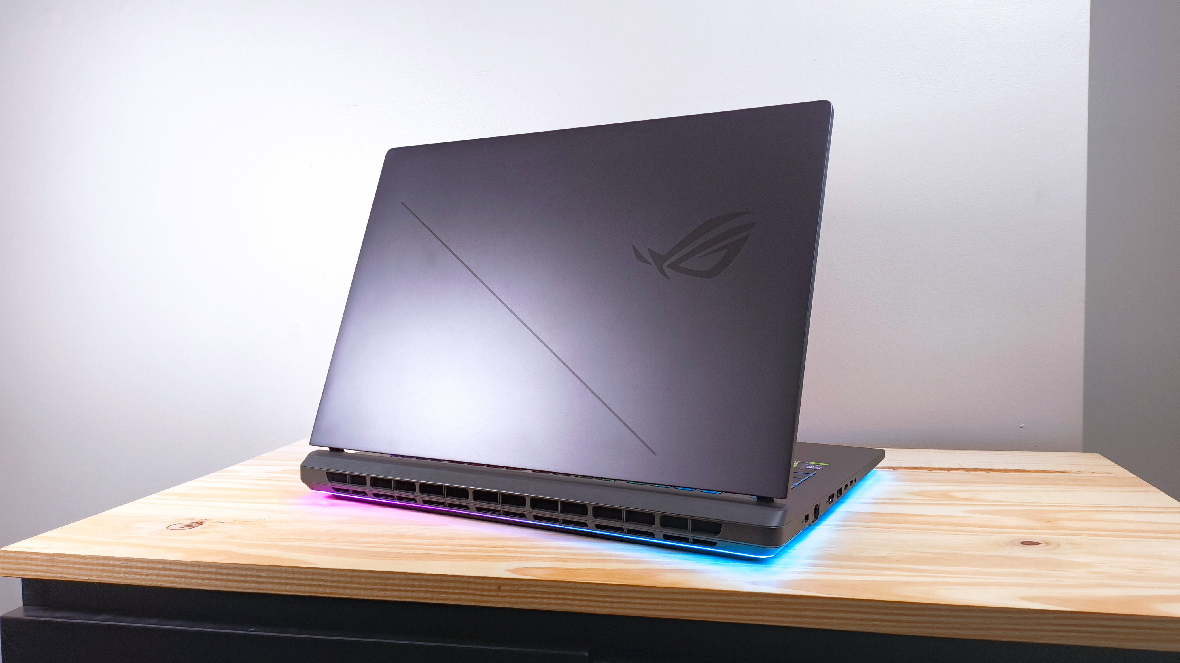 The Asus ROG Strix G18 seen from behind on a wood table with lid open