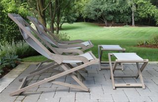 A pair of wooden deckchairs next to a lawn