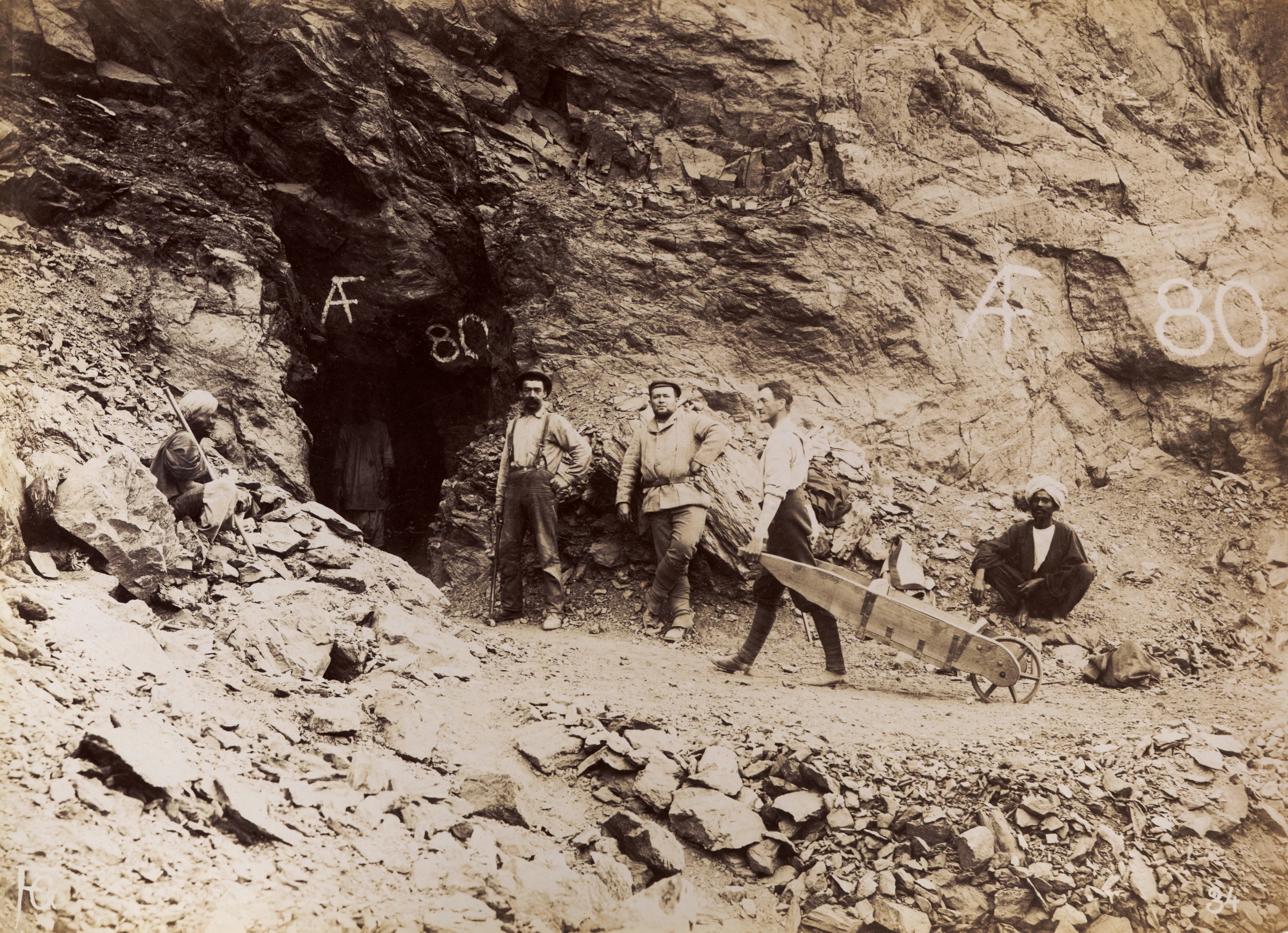 A sepia image of four men standing outside the entrance to an emerald mine