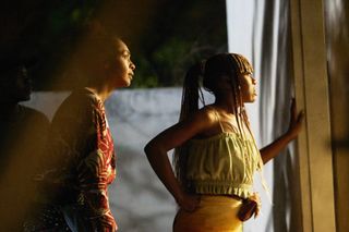 two women look shocked out of a window in a still from on becoming a guinea fowl