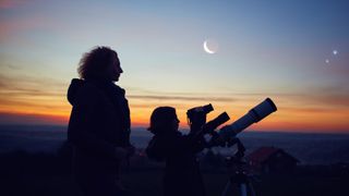 mother and daughter viewing night sky with a telescope