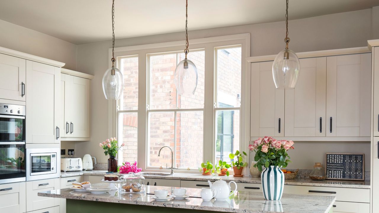 Large window in kitchen, with light units and large central island with pendant lights above