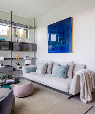 Modern living room with mezzanine, gray sofa, white walls, large blue painting