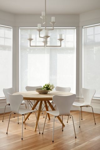 A breakfast room with a round dining table and white walls