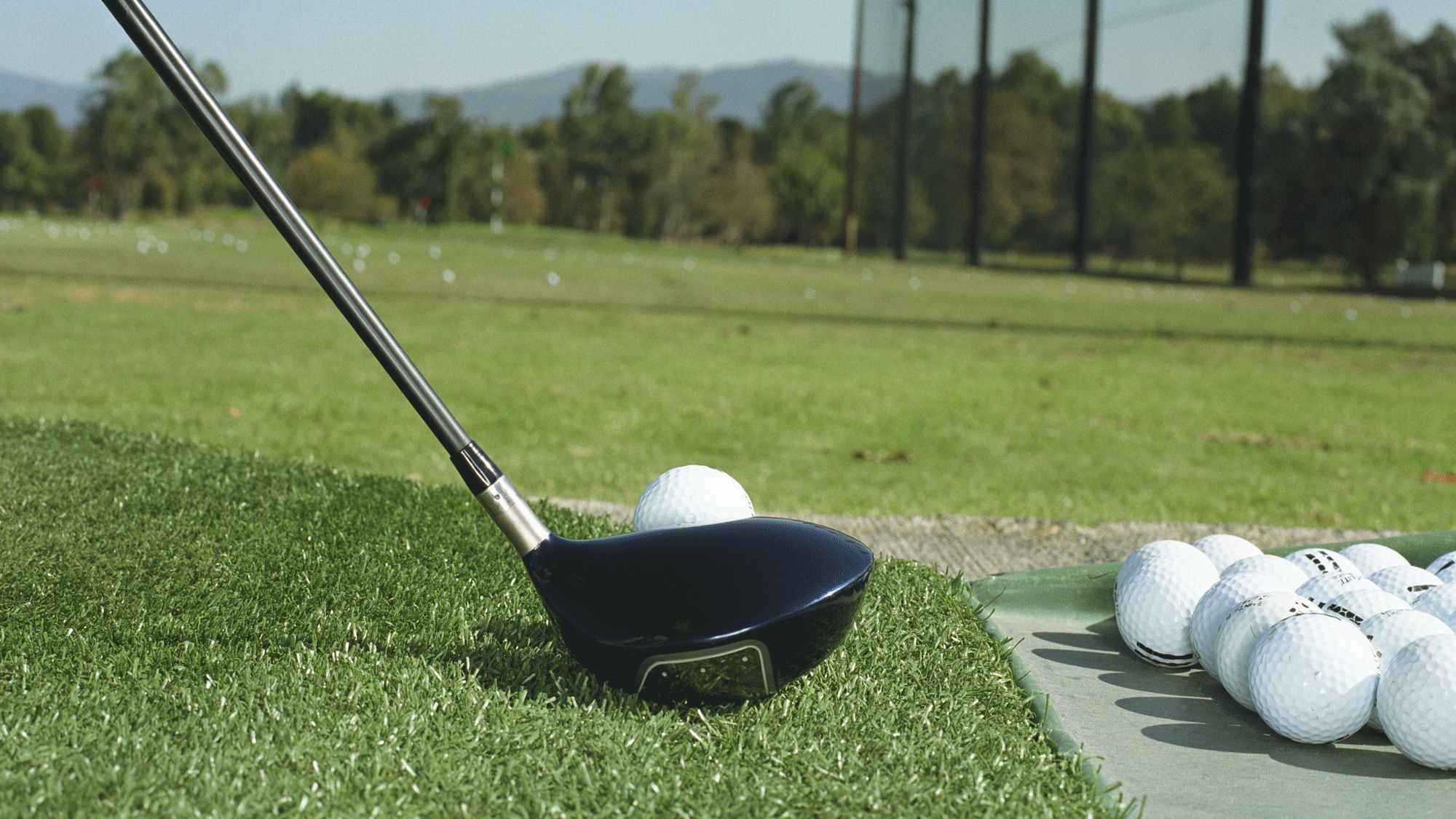 Club lined up with golf ball on driving range 